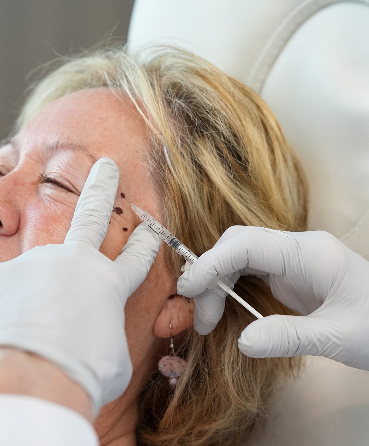 Administering a cosmetic injection to a woman.