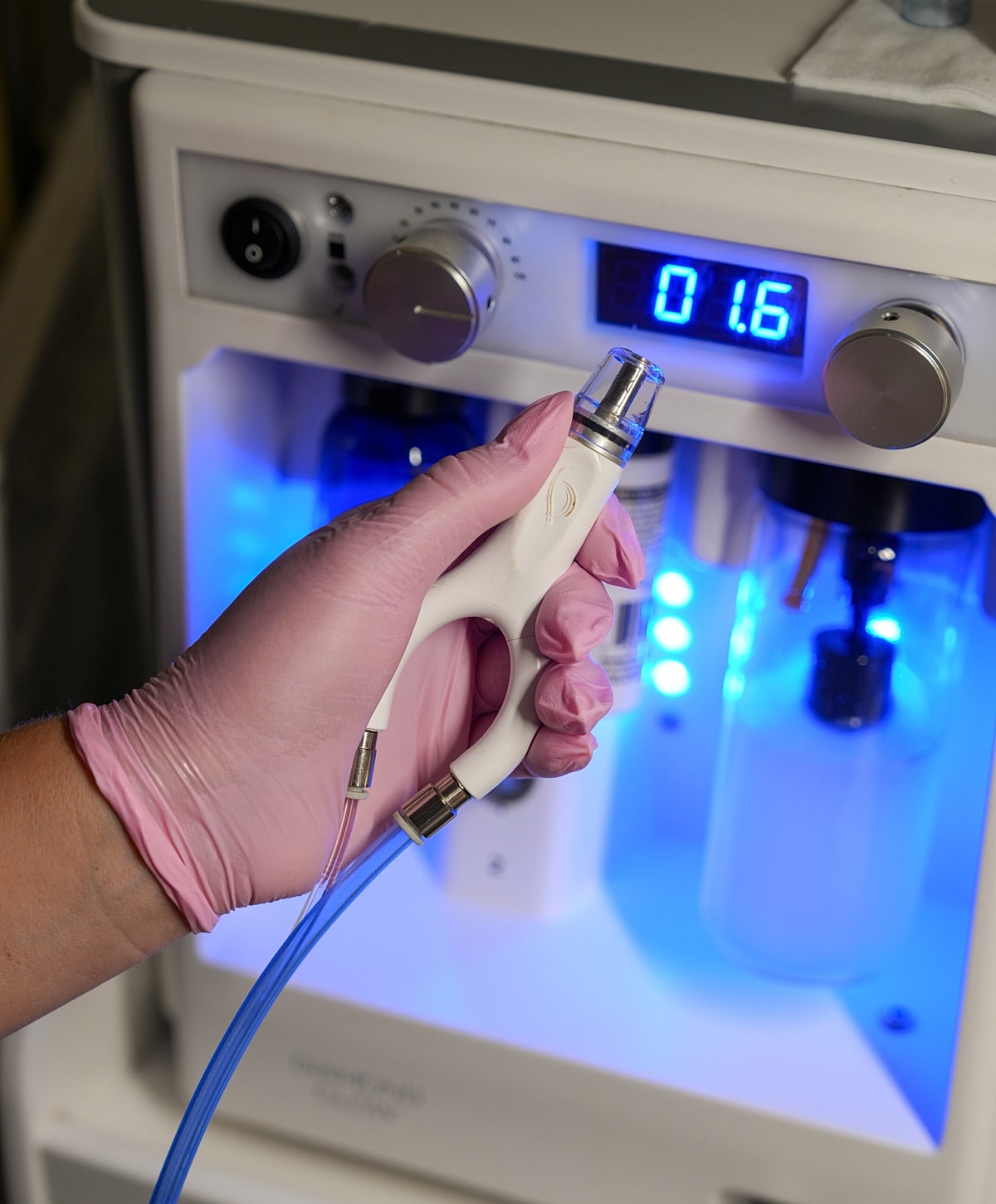 Cosmetic device held by gloved hand.