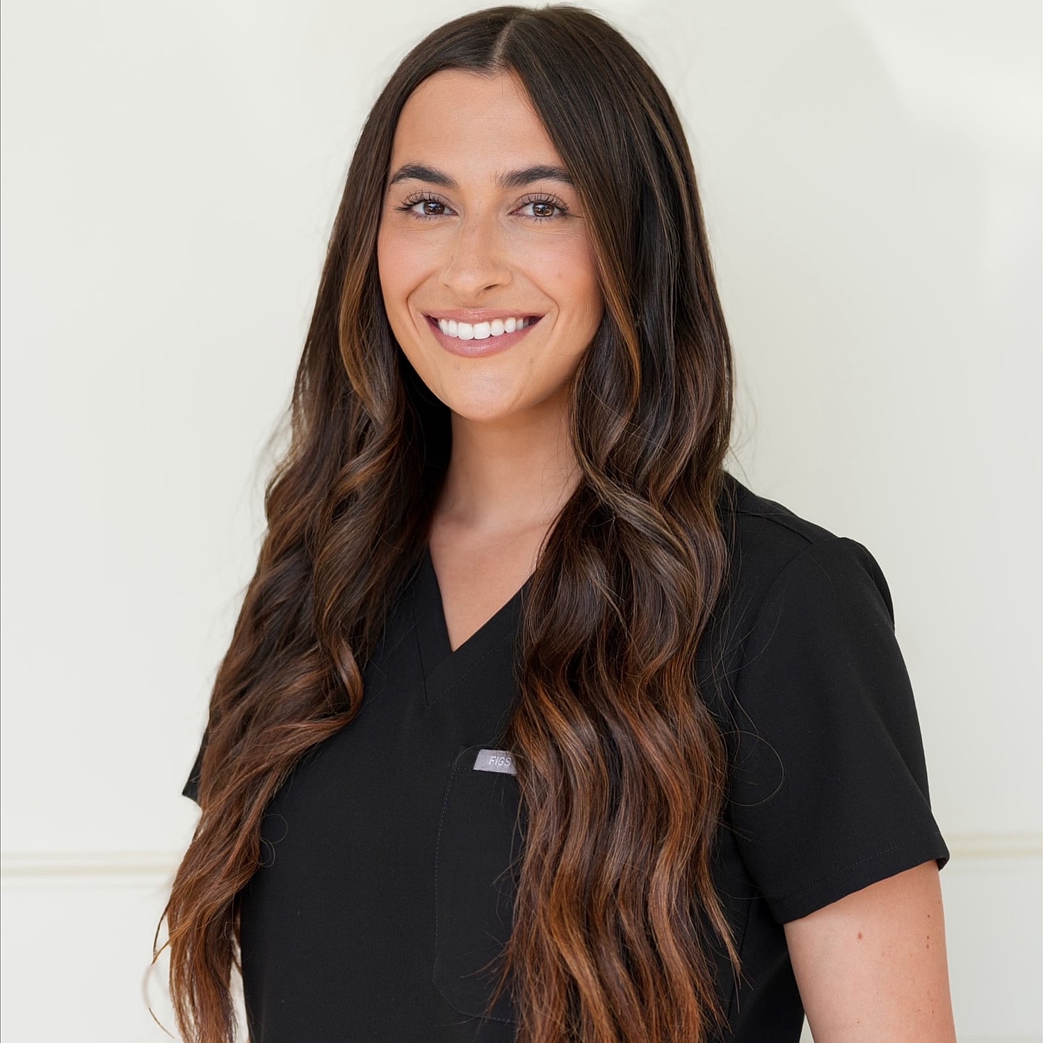 Smiling woman in medical attire with long hair.